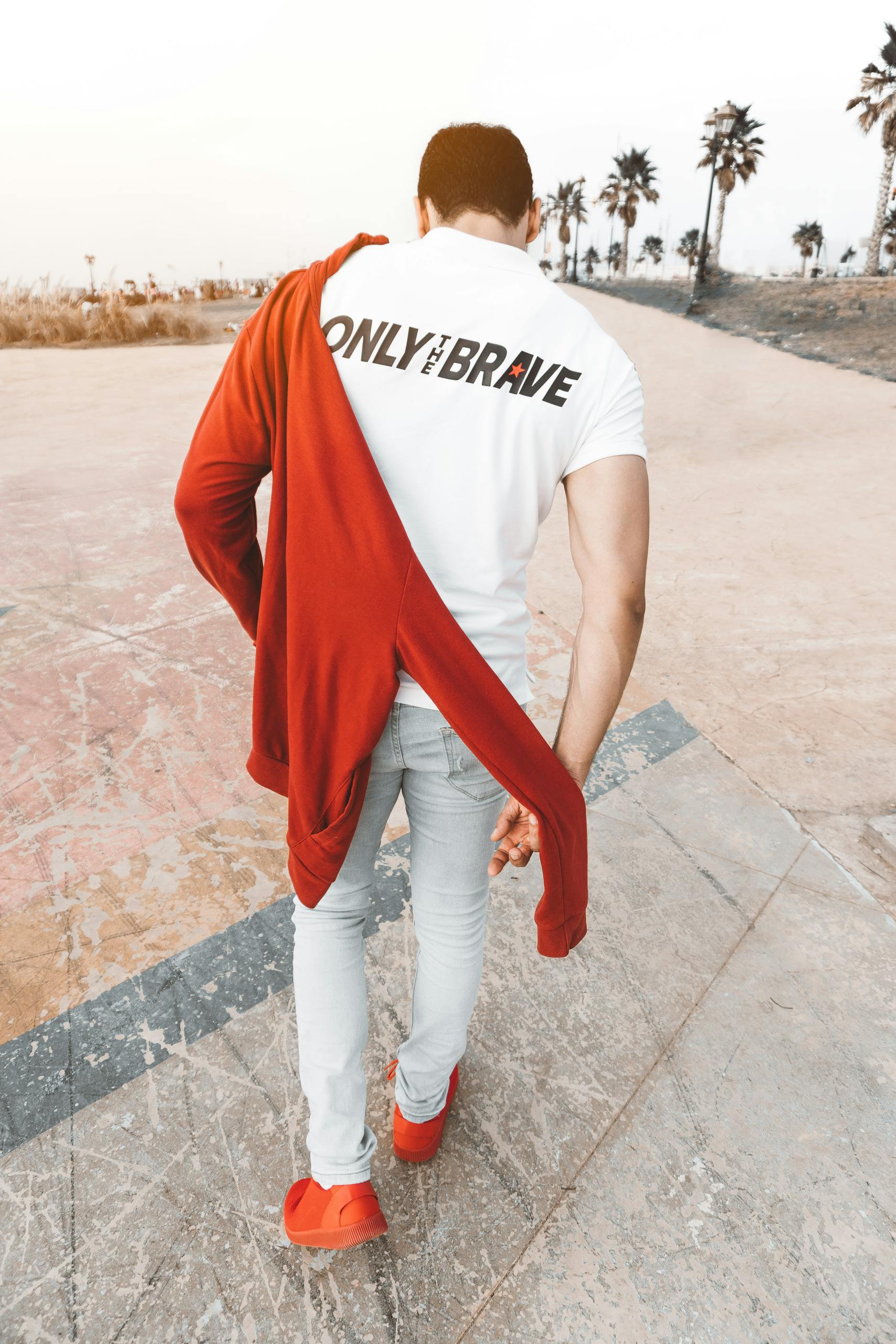 A man with red jacket and modern outfit walking outdoors in Rabat, showcasing urban style.