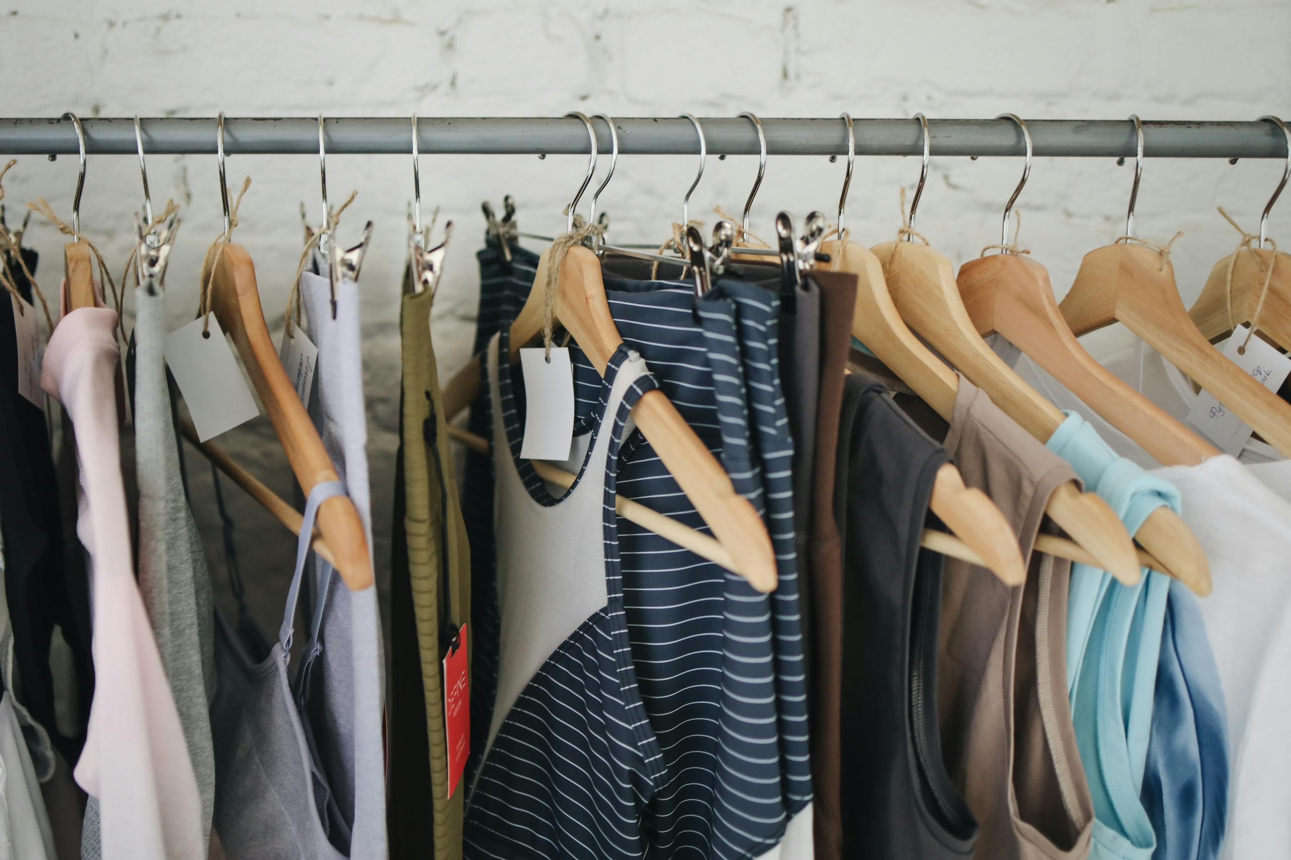 A variety of casual clothing items hanging on wooden hangers in a fashion boutique.